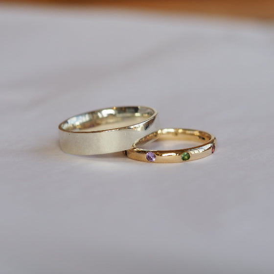 Two gold rings with gemstones on a light fabric background