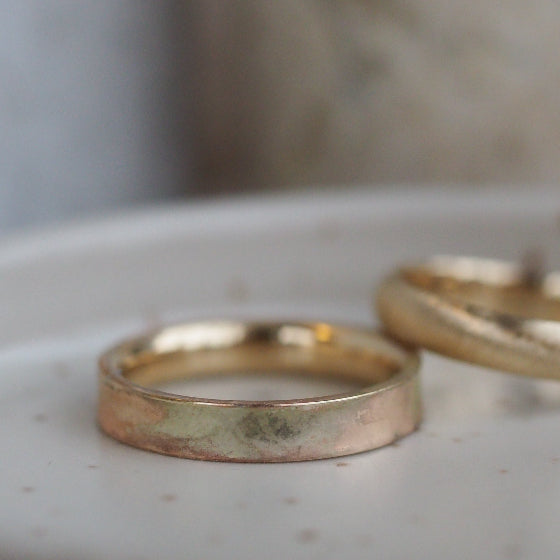 Two gold rings on a textured surface with a blurred background