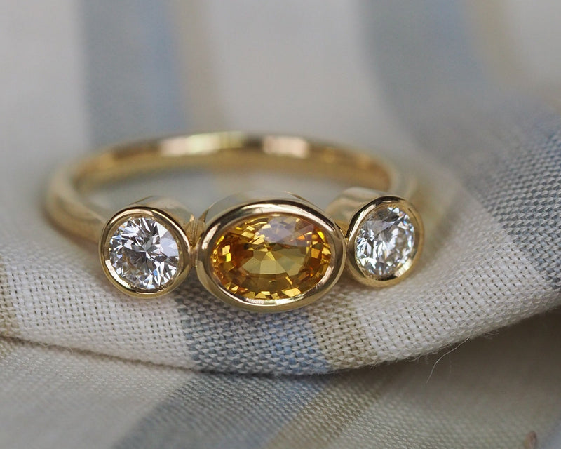 a yellow gold ring in a striped fabric backdrop
